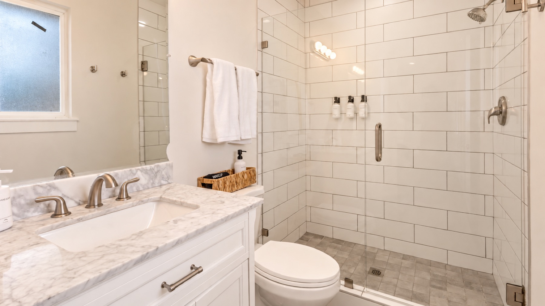 The upstairs bath: subway tile, a glass shower with a rain head, and a granite vanity.