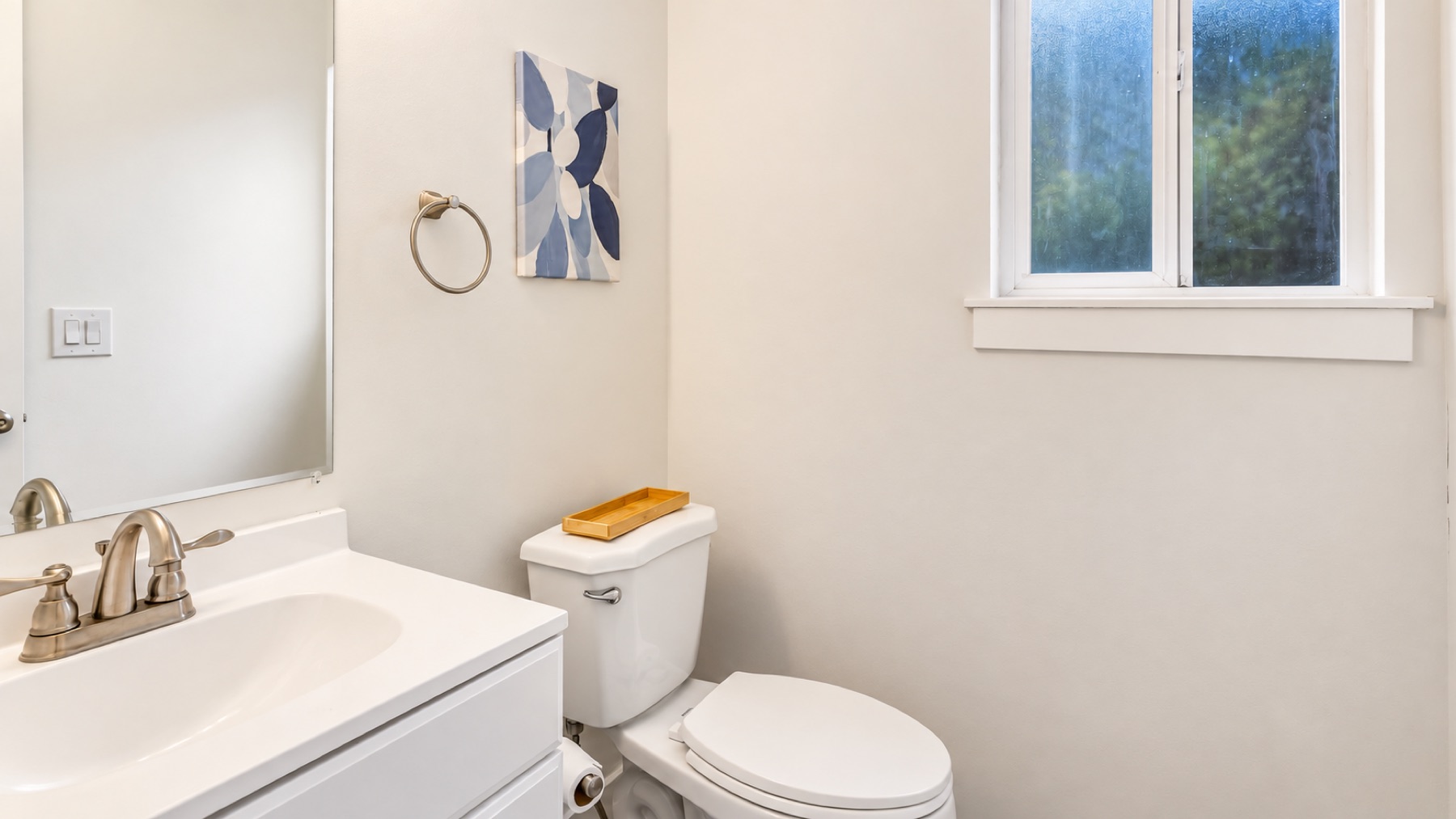 The powder room downstairs: a white vanity, a blue leaf print, and a window you can open.