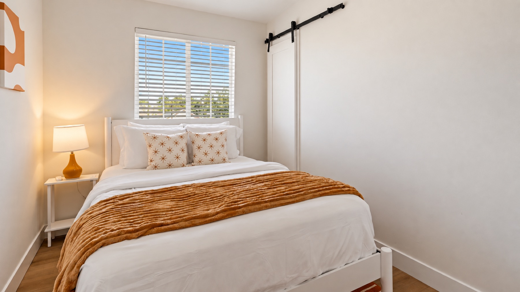 Bedroom three: a rust throw, star-patterned pillows, and a barn door that slides shut.