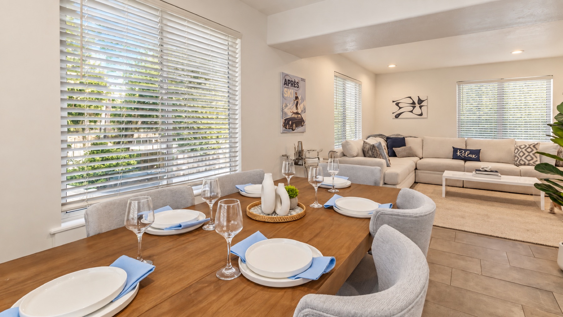 The dining table set for six in blue and white, with the living room and its long sectional behind.