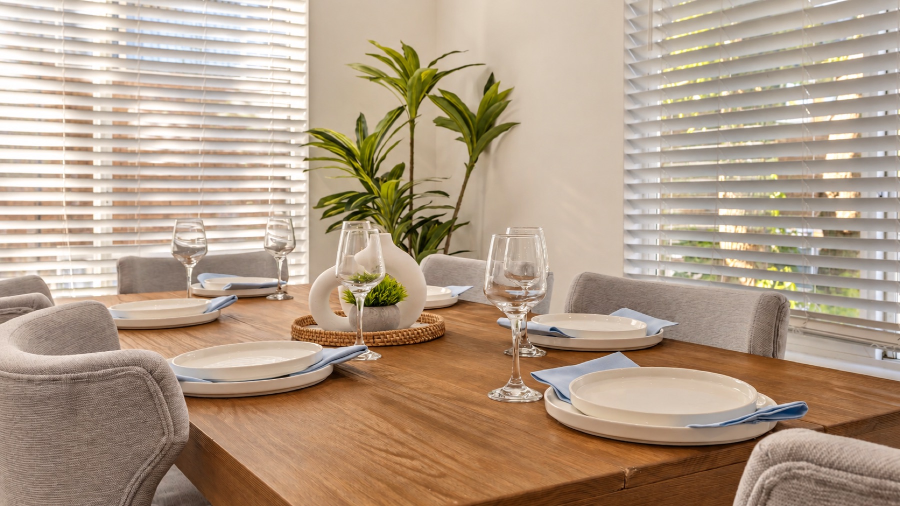 Place settings up close: white plates on blue napkins, a wine glass each, and the plant in the middle.
