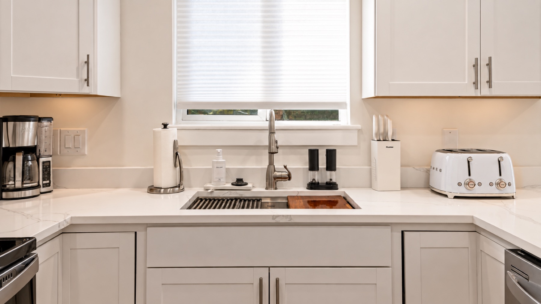 The sink corner: a farmhouse sink, a wooden board, the knife block, and a four-slice toaster.