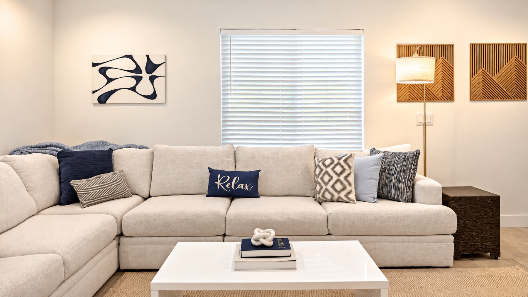 The corner of the sectional: a navy throw, a chevron pillow, and one that says Relax, which is the house rule.