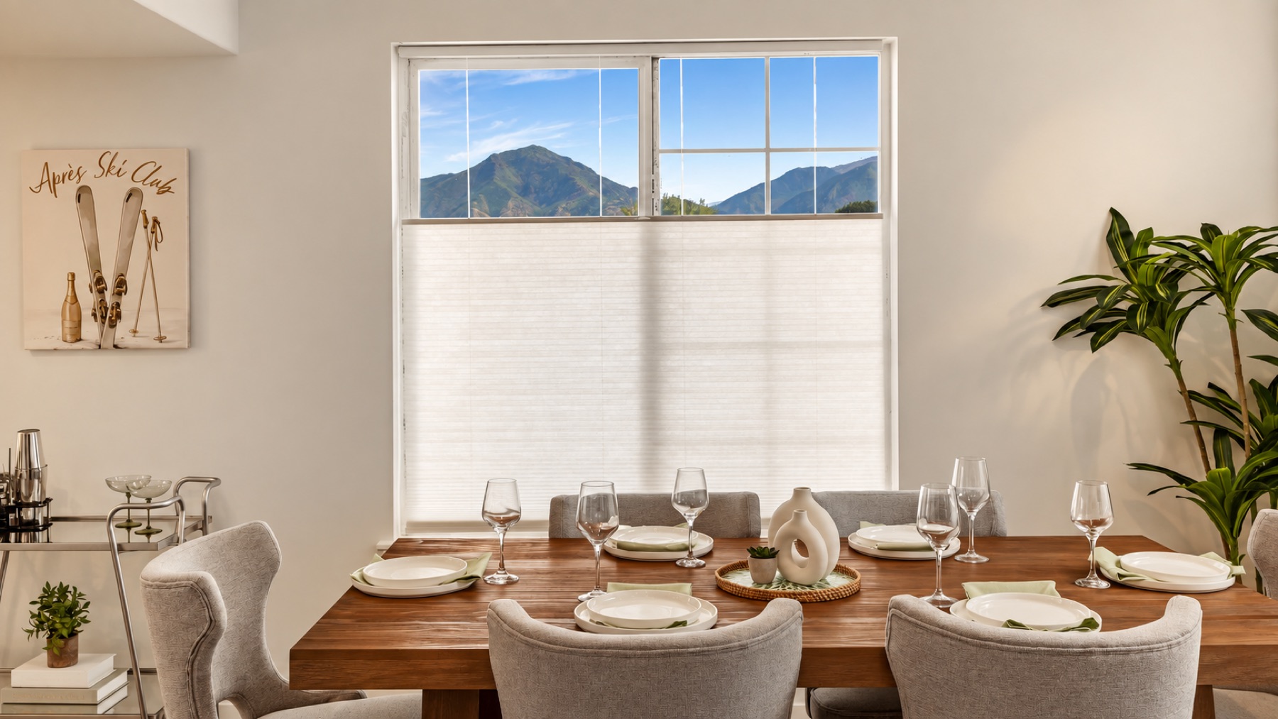 The dining table set for four, with a mountain ridge framed in the window behind it and the Après Ski Club print on the wall.