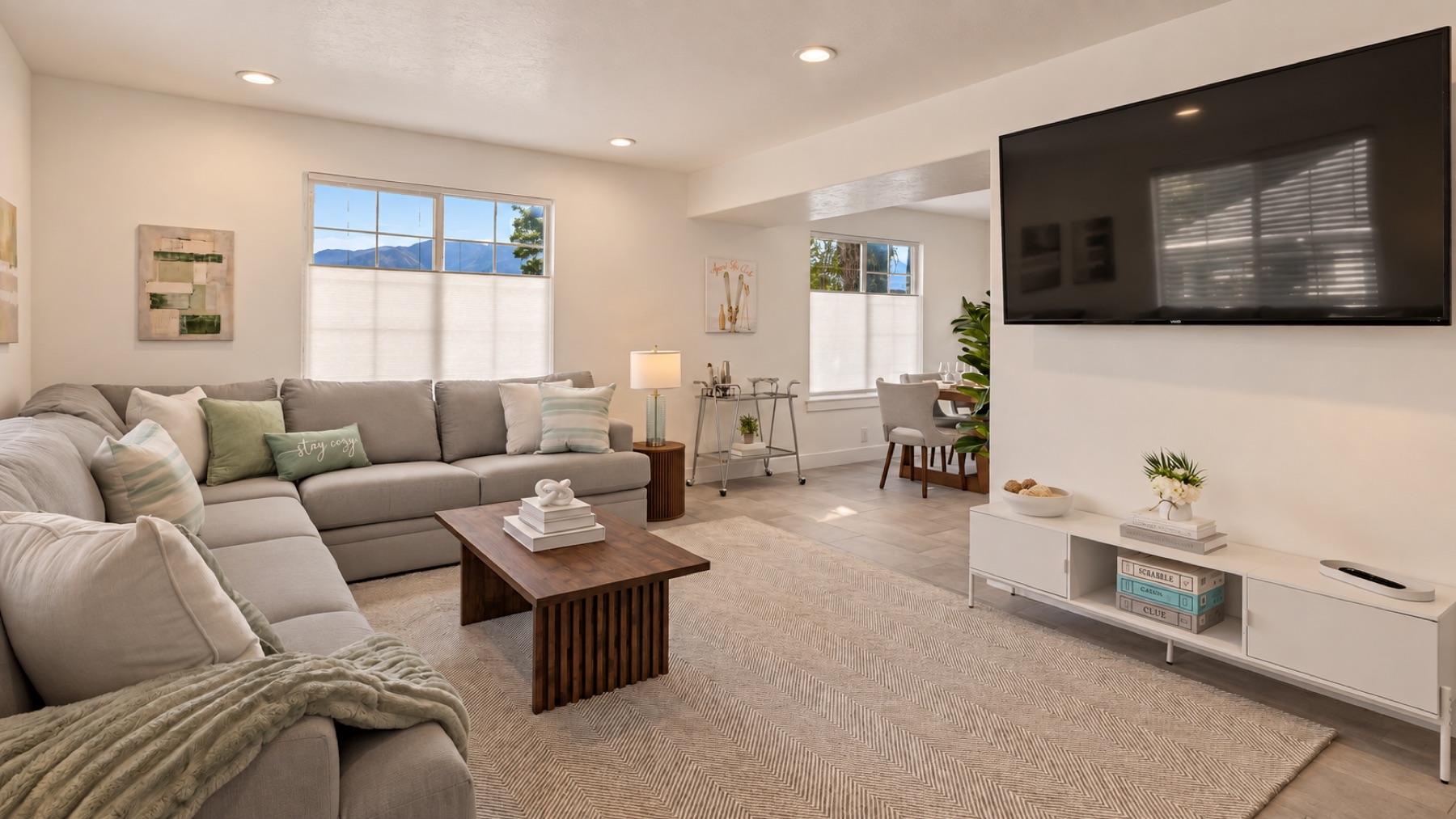 The same room from the door: the sectional, the walnut table, and the screen for the snow report.