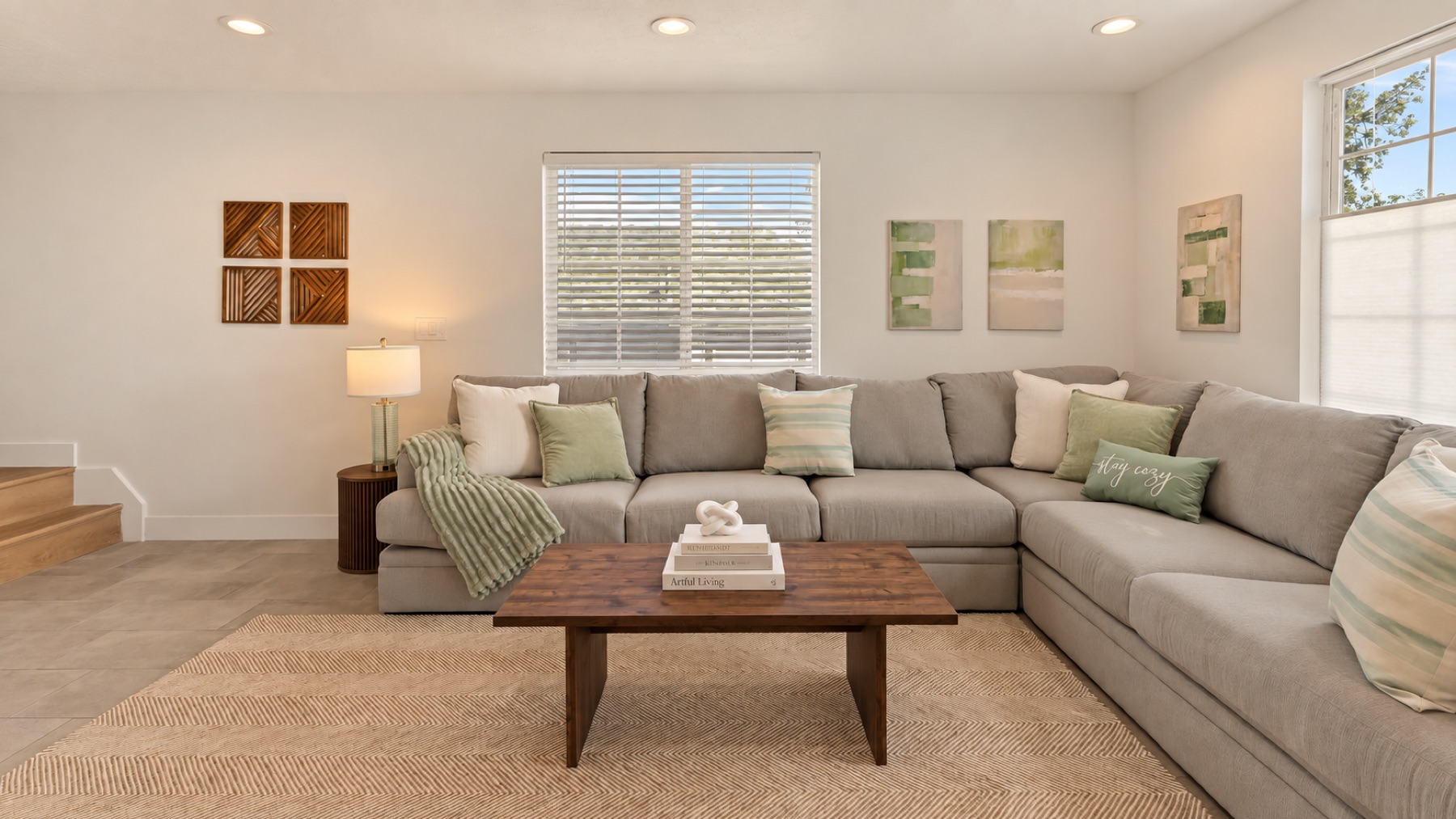 The corner everyone ends up in: the long side of the sectional under three small landscapes.