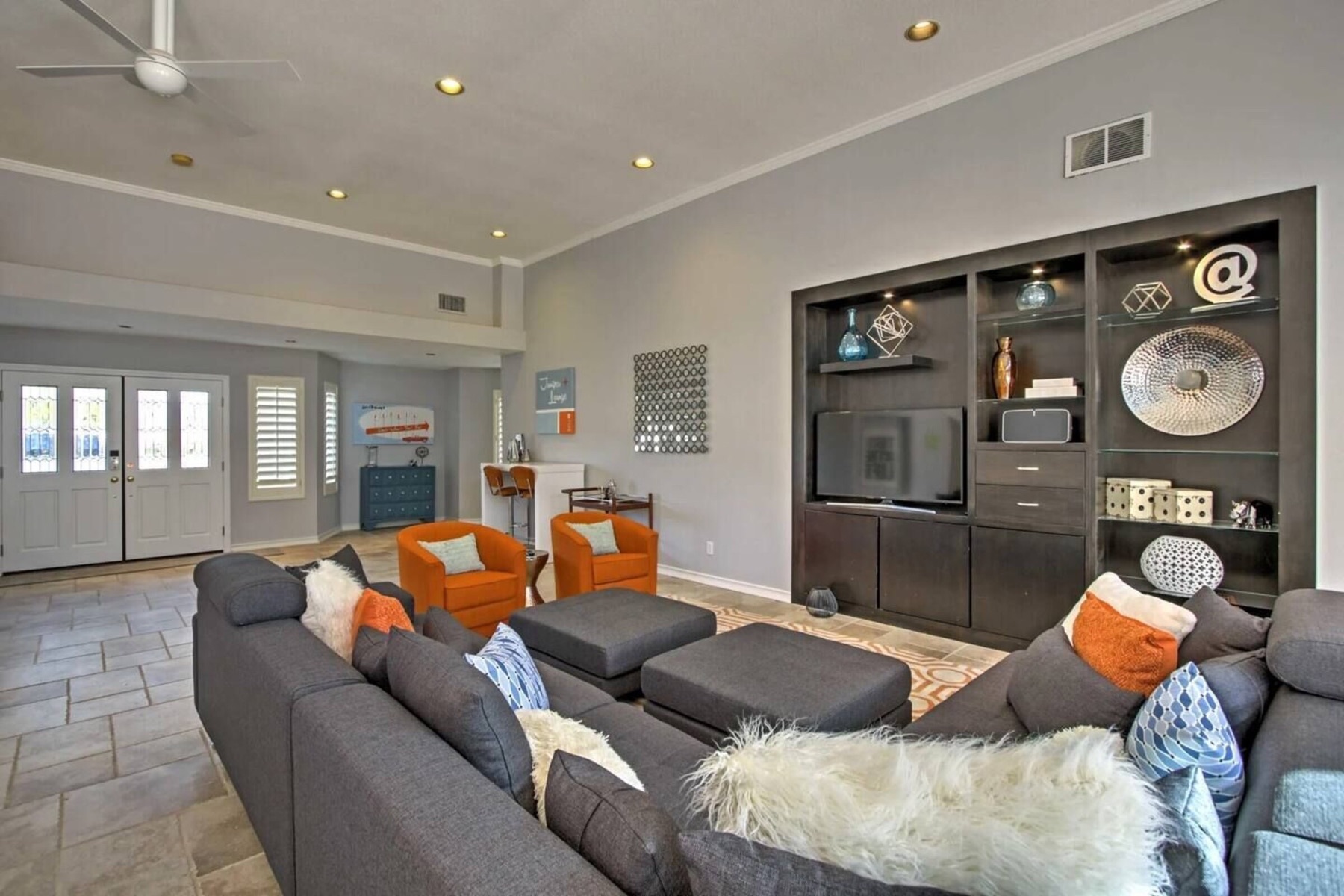 The great room — grey sofas, orange chairs, twelve-foot ceilings