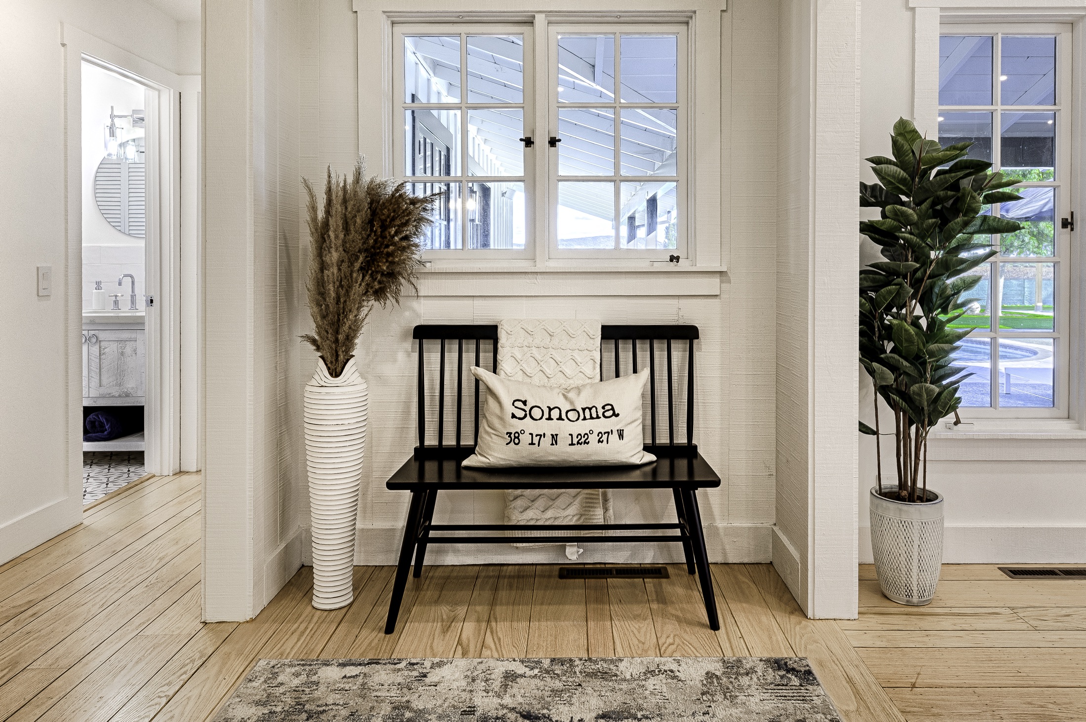 The entry — a black Windsor bench with a Sonoma pillow, pampas grass in a white vase