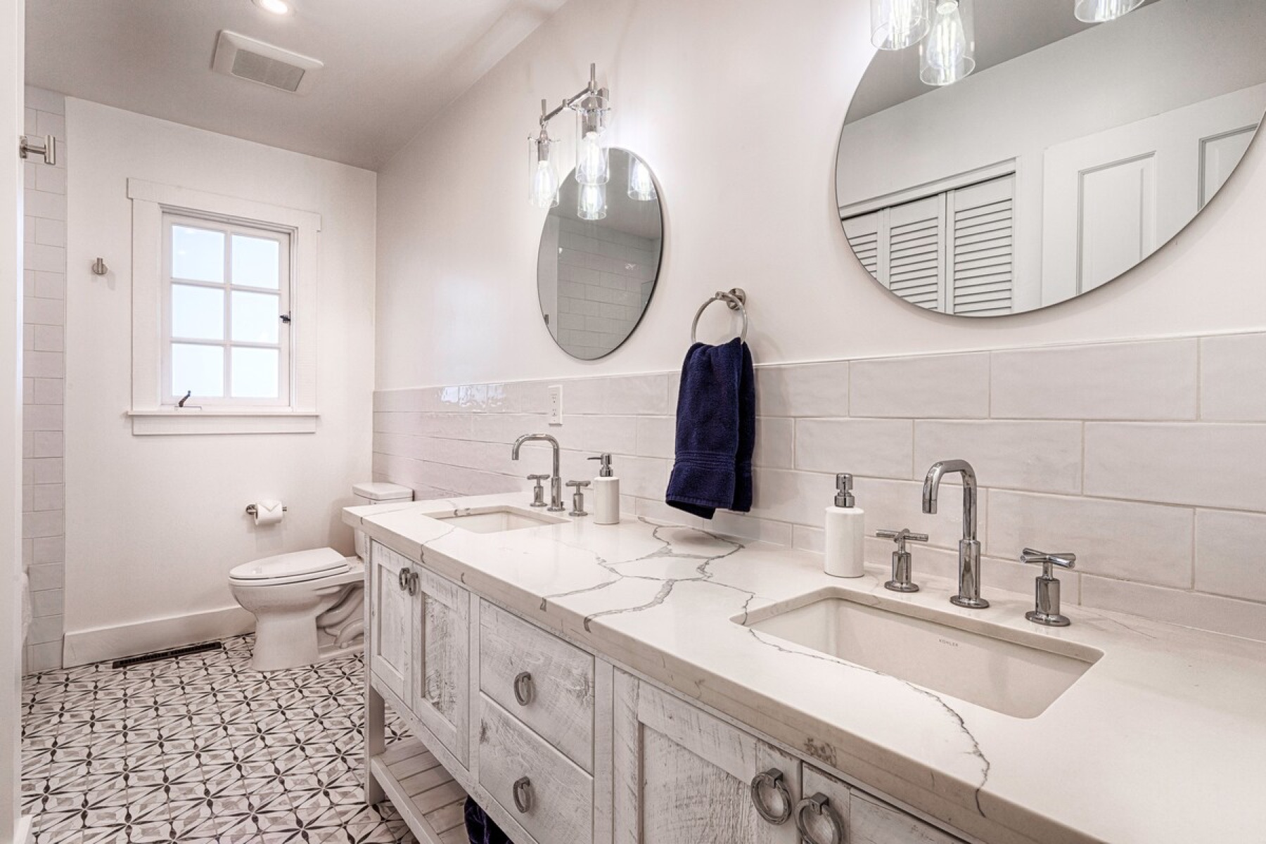 The hallway bath — tub and shower, round mirrors, double vanity