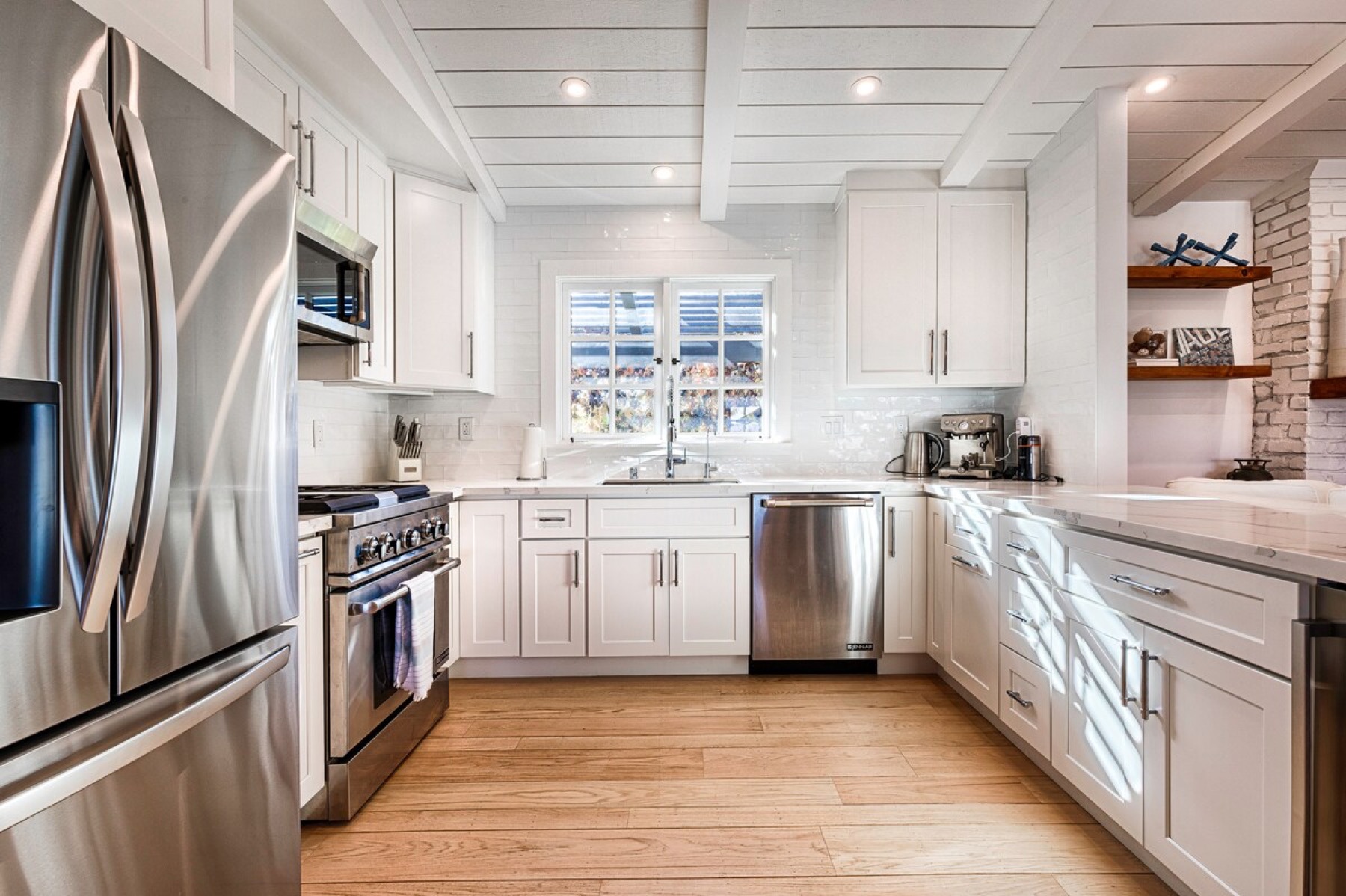 The kitchen — white cabinetry, new appliances, wine fridge