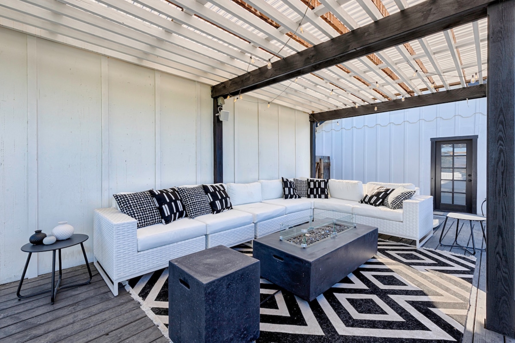The pergola lounge — white sofas around a fire table under the shade