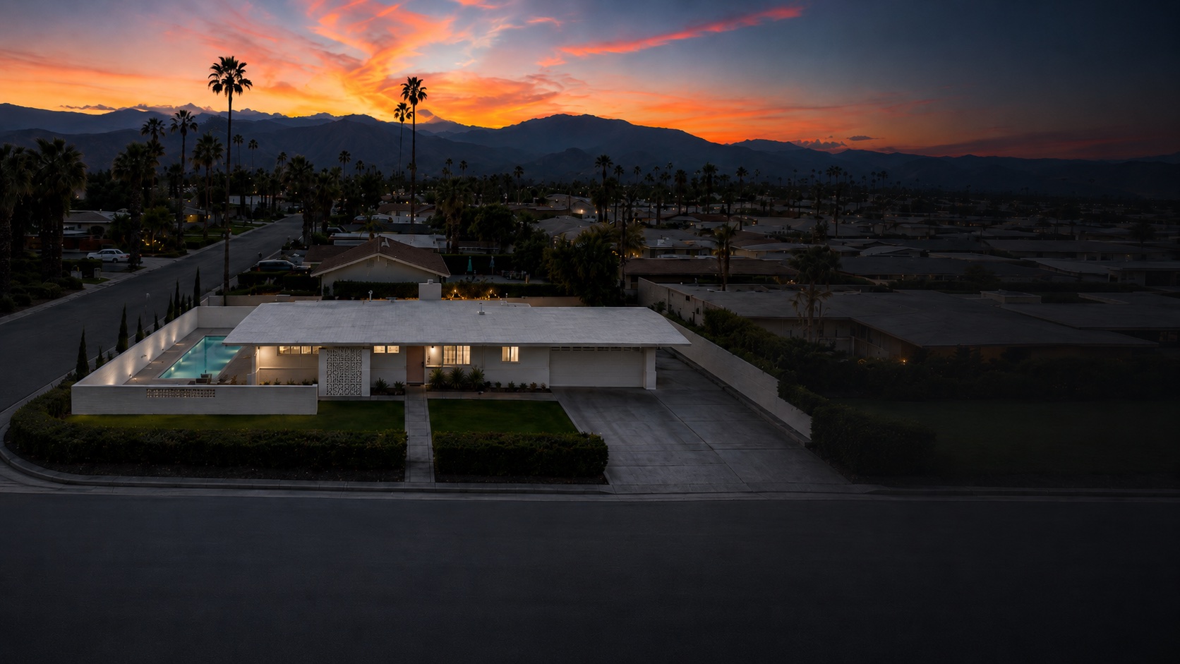 Atomic Kat House at dusk — the low white house and lit pool under a Santa Rosa mountain sunset