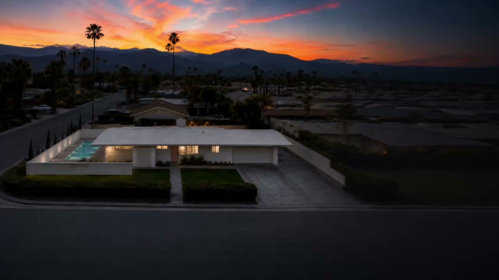 The house at dusk on its corner lot, palms and the Santa Rosa range catching the last of the sunset behind South Palm Desert